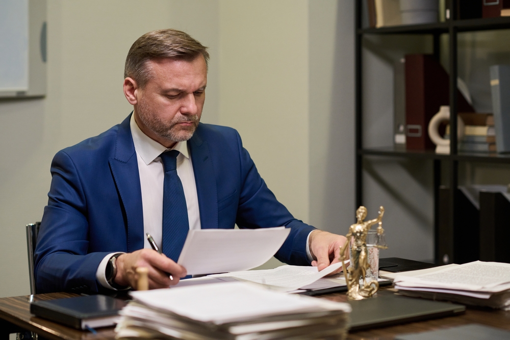 Middle,Aged,Caucasian,Man,Sitting,At,Desk,Reviewing,Legal,Documents,
